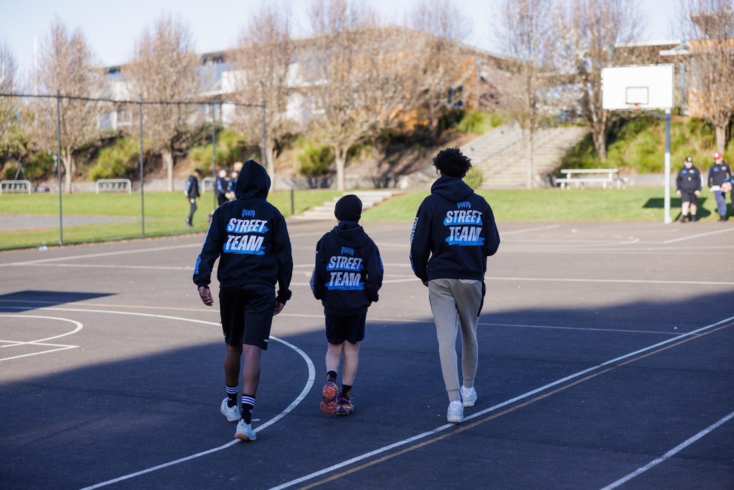 Three JCP Youth Street Team staff together on a basketball court
